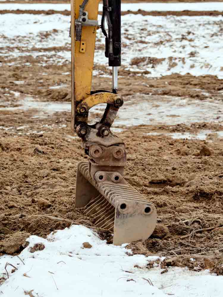 Price Busters plumbing technician digging frozen ground above a water line/ excavating frozen ground