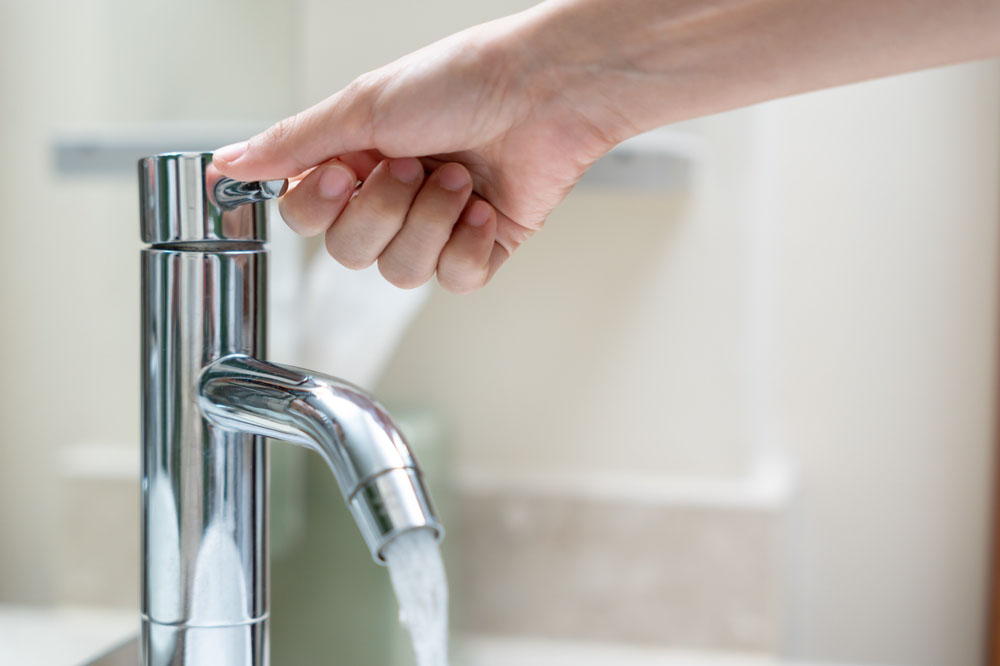 A person turning off a faucet